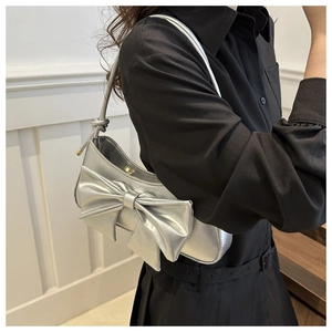 Detailed view of silver bow-knot handbag with crocodile texture and metallic finish