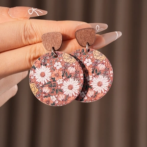 Close-up of vintage round wooden earrings with hand-painted white and orange floral patterns