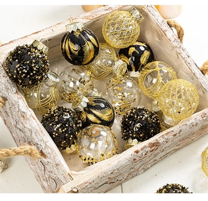 Detail of Christmas balls with black, gold sequins and feather patterns on a wooden tray