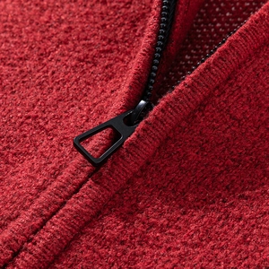 Nahaufnahme der roten Strickstruktur und des schwarzen Reißverschlusses dieser Jacke