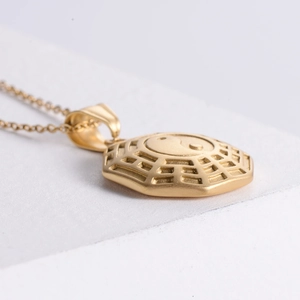 Macro shot of a golden octagonal Tai Chi pendant with Bagua patterns on a textured surface