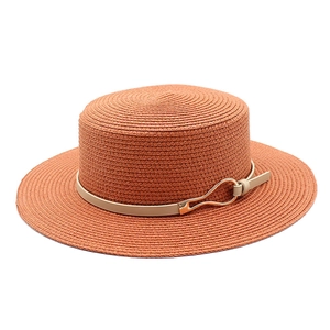 Detail of caramel boater hat with a beige leather band and a gold metal buckle