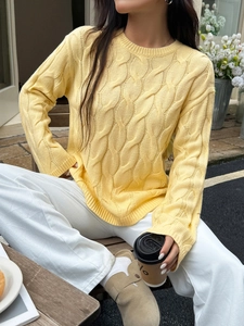 Close-up of yellow round neck long sleeve cable knit sweater with textured patterns