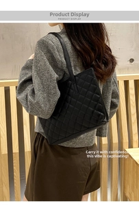 Close-up of a large black quilted tote bag with diamond pattern carried by a model