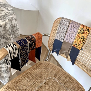 Détail de foulards en soie aux motifs animaliers et floraux drapés sur une chaise