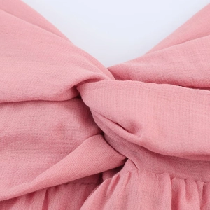Detail of pink midi dress showing intricate knot design and woven fabric texture