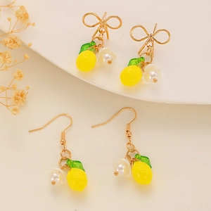 Detail of yellow lemon earrings with green leaves, white flowers, and golden bows