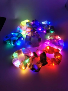 Macro shot of colorful LED scrunchies glowing in the dark with satin fabric texture