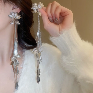 Gros plan détaillé des boucles d'oreilles pampilles feuille en argent avec fleurs et chaînes