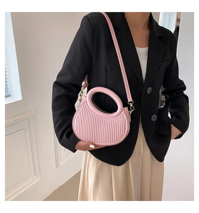 Pink saddle bag with vertical pleat texture and unique hollow handle shown on model