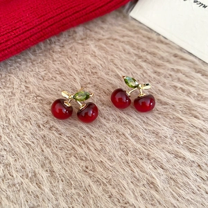 Detailed shot of cherry earrings with red resin spheres and green zircon leaves