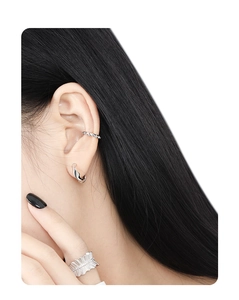 Macro detail of silver irregular twist earrings and textured feather band ring on model