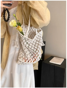 Detail of hand-woven hollow mesh tote bag with tassels and decorative flowers inside