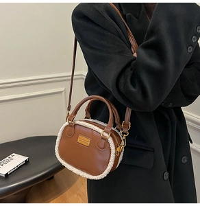 Detail of plush faux shearling trim on a brown leather crossbody pillow handbag