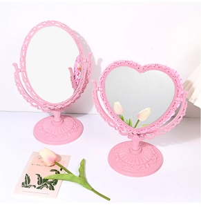 Pink European style heart and oval vanity mirrors on a tabletop with floral decor