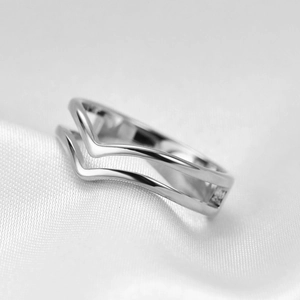 Detail of interlocking V-shaped silver ring on white silk texture with macro focus