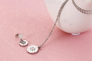 Macro view of silver necklace and earrings with Roman numerals and centered crystal stones