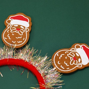 Gros plan d'un serre-tête de Noël en velours rouge avec motifs Père Noël et guirlandes