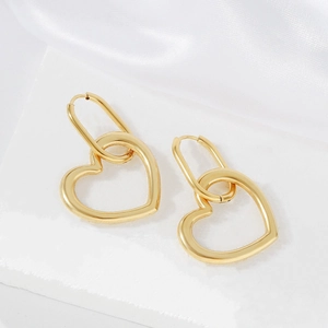 Elegant gold hollow heart earrings with oval clasp on white silk and stone display