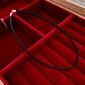 Detail view of a black faux leather choker with silver lobster clasp in a red jewelry box