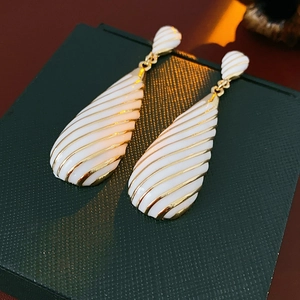 Détail de boucles d'oreilles vintage en émail avec rayures dorées sur un écrin vert