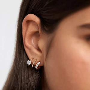Elegante driedelige set gouden oorbellen met vierkante zirkoon en kristallen op een model