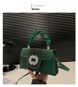 Close-up of dark green faux crocodile handbag featuring a luxury crystal square buckle