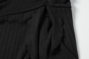Macro shot of black ribbed knit fabric detail showing fine stitching and soft texture