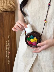 Detail of bohemian coconut shell mini bag holding headphones with colorful wood accents