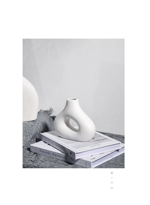 Detailweergave van moderne witte keramische vaas met hol ontwerp op boeken