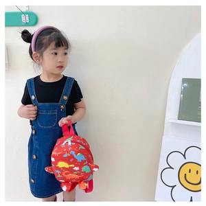 Close-up of children's red backpack featuring colorful cartoon dinosaur prints and fabric