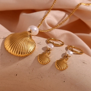 Detailed view of 18K gold plated seashell necklace and pearl earrings on silk fabric