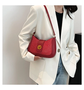 Close-up of a red woven crossbody bag with gold buckle on a white blazer model