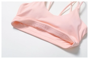 Vue détaillée du soutien-gorge de sport rose avec fines bretelles croisées et large ourlet