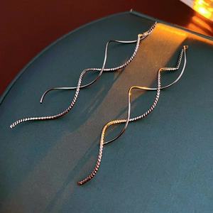 Détail macro des boucles d'oreilles argentées ondulées avec finition métallique texturée
