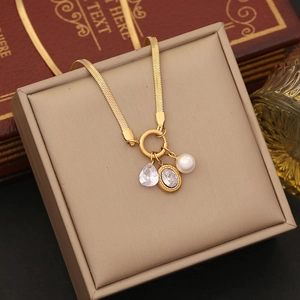 Detailed macro of golden snake chain necklace with zircon pendants and white pearl detail