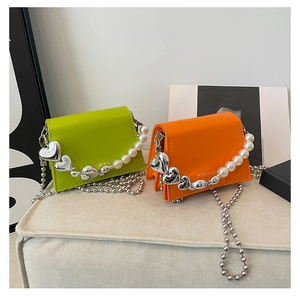 Detail of neon green and orange mini square bags with pearl handle and silver heart charm