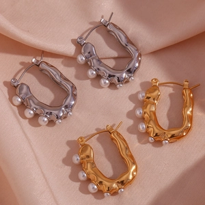 U-shaped stainless steel pearl earrings in gold and silver finish on silk background