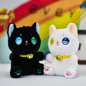 Detailed close-up of cute black and white kitten plush toy pendants featuring tiny gold bells