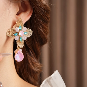 Close-up of vintage gold floral earrings with pink and blue gemstones on a model