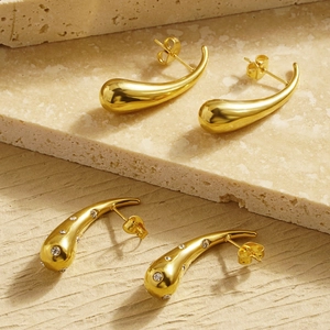 Elegant gold drop earrings with polished finish and cubic zirconia inlay on stone background