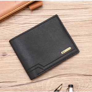 Detail of black leather wallet with geometric stitching and metal tag on wooden desk