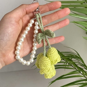 Detail of handmade crochet lily of the valley keychain with white pearls and silver clasp
