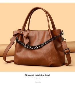 Detail of a brown PU leather handbag featuring a large bow and decorative black metal chain