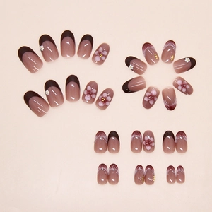 Detail of French style press-on nails with 3D floral accents and cat-eye brown finish