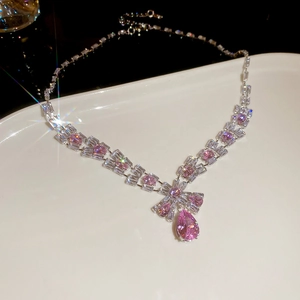 Close-up of pink teardrop zircon necklace and earrings set on white ceramic plate