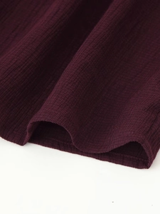 Close-up of wine red ribbed knit fabric texture with elegant wavy hem detail