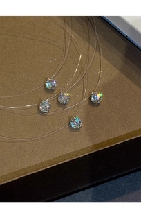Dettaglio di cinque zirconi tondi scintillanti su una collana in filo di nylon invisibile