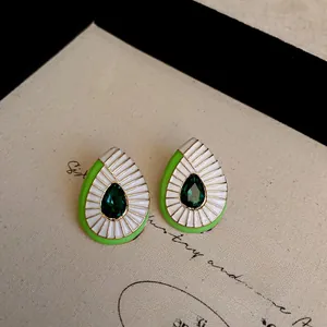 Detailed macro view of teardrop enamel earrings with dark green center stone and gold edges
