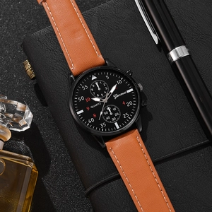 Business quartz watch with brown leather strap displayed next to a pen and perfume